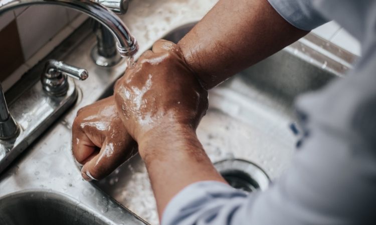 personne qui se lave les mains au robinet